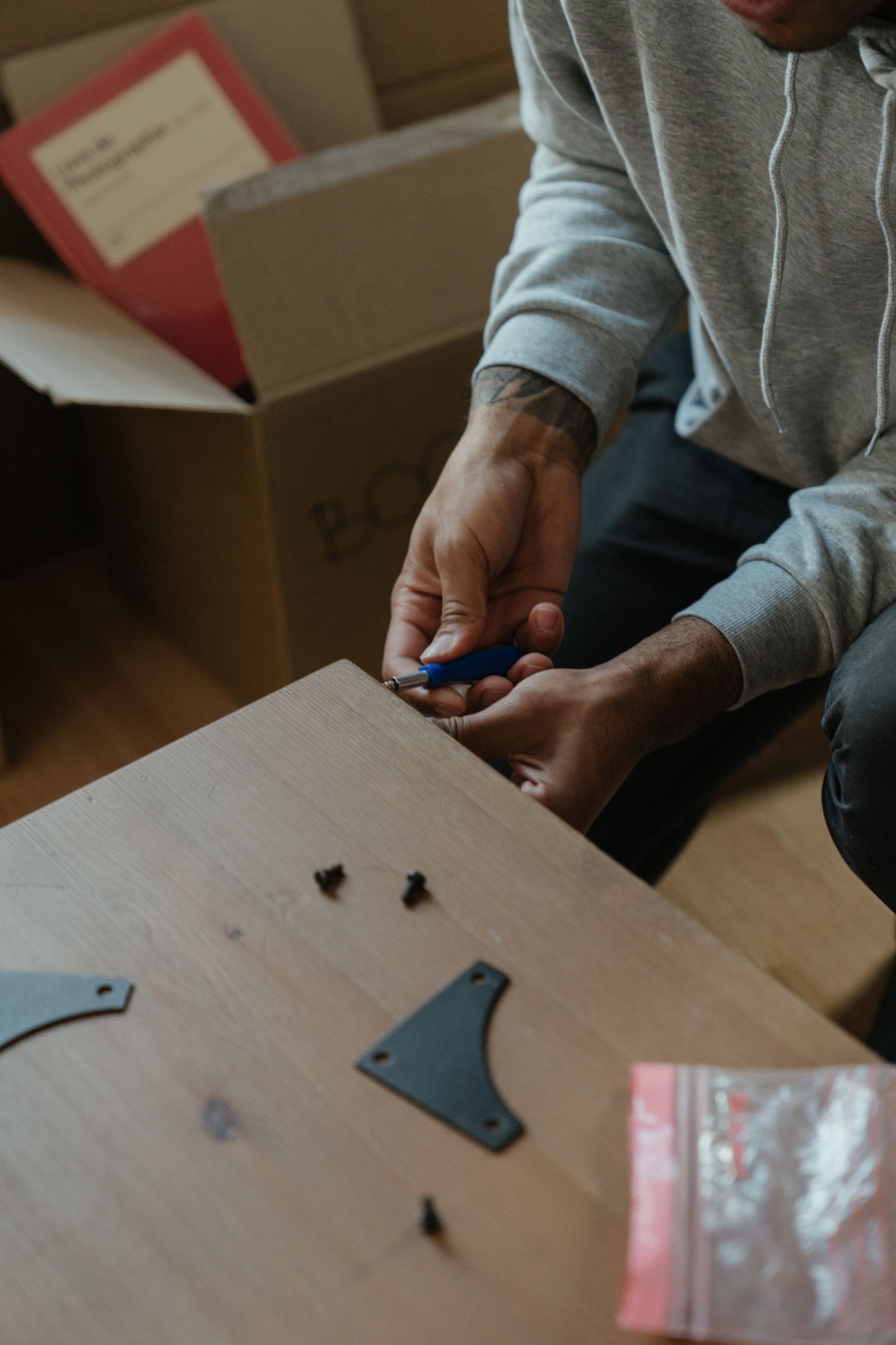A man assembling a piece of wooden furniture in a new apartment, demonstrating reassembly after a move
